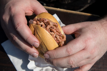 Mann isst Nordseekrabben Brötchen als Fischbrötchen auf Fischmarkt an Holztisch als schneller regionaler Imbiss