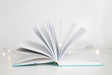 open book sheets fan on white background bokeh garland closeup