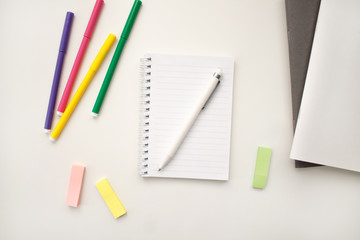 white notebook with springs sheets in line on a white background with a white pen markers colored stickers lying next to notebooks