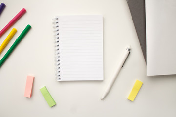white notebook with springs sheets in line on a white background with a white pen markers colored stickers lying next to notebooks