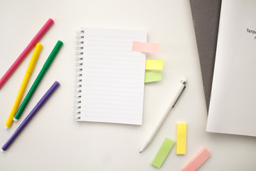 white notebook with springs sheets in line on a white background with a white pen markers colored stickers lying next to notebooks