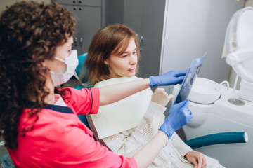 family house dentist shows an x-ray. a young woman sitting at a reception near a dentist. Girl dentist