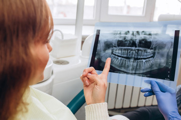family house dentist shows an x-ray. a young woman sitting at a reception near a dentist. Girl dentist