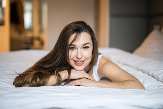 Beautiful day dreamer. Beautiful young woman holding hands behind head while lying in bed and smiling