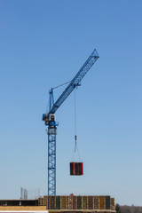 A construction crane moves the load. Building materials on pallets are moved by crane. Construction of a modern residential building