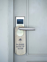 The hotel room with PLEASE MAKE UP ROOM sign on the door, Wood room label hanging on door handle