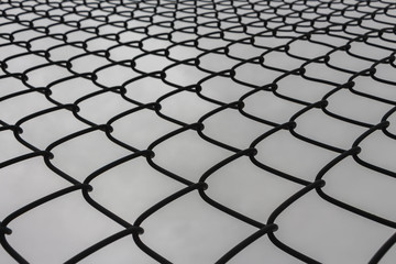 Looking Looking up at the protective metal fence and iron mesh outside the city sports fieldup at the protective metal fence and iron mesh outside the city sports field