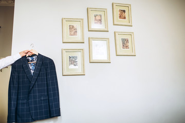 stylish groomsmen helping happy groom getting ready in the morning for wedding ceremony. luxury man in suit in room. wedding day.