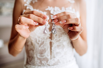 Beautiful earrings on the palm of the bride