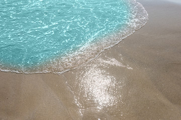 Soft wave of turquoise sea water on the sandy beach.