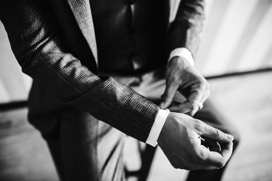 stylish groomsmen helping happy groom getting ready in the morning for wedding ceremony. luxury man in suit in room. wedding day.