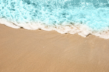 Naklejka na ściany i meble Soft wave of turquoise sea water on the sandy beach.