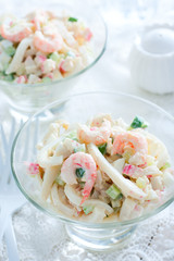Salad with squids, shrimps, crab sticks in glass vases, selective focus