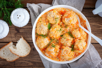 Meatballs with rice, hedgehogs, in tomato-sour cream sauce on a wooden table, top view, horizontal