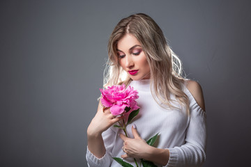 Young beautiful healthy blond girl with pink flower. Female fashion concept. space for text