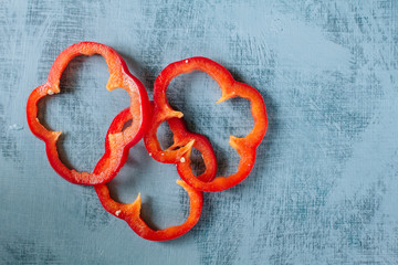 A set of sliced pieces of red pepper on a blue wooden background with a texture and copy space