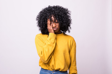 Sad pretty girl feeling upset while spending time at home alone. Beautiful young dark-skinned female with Afro hairstyle staring at camera with unhappy or regretful look against studio wall - Powered by Adobe