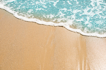 Naklejka na ściany i meble Soft wave of turquoise sea water on the sandy beach