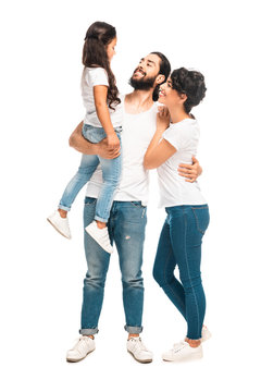 happy latin man holding in arms cute daughter while standing with attractive wife isolated on white