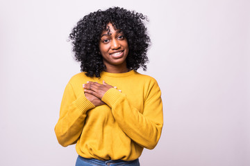 Friendly looking female with Afro hairstyle, keeps hands on chest, feels hands on heart, looks joyfully isolated over white background. I am moved to tears
