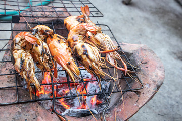 Delicious grilled prawns on flaming grill. Burnt shrimp cooking seafood on stove.