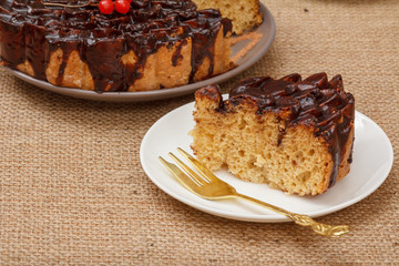 Chocolate cake and a slice of it on plate with fork.