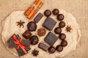 Chocolate candies various shape and chocolate bars with nuts on pack paper.