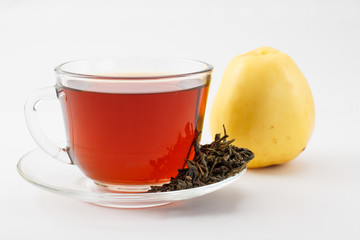 Glass cup of tea on saucer with dry leaves of green tea and apple