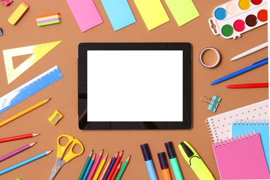 Modern digital tablet and school stationery on a colored background top view. Kontpt back to school. Place for text.
