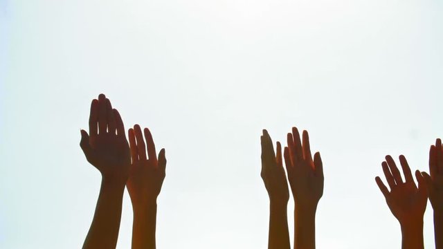 Tracking shot of human arms raised against the sky and wiggling