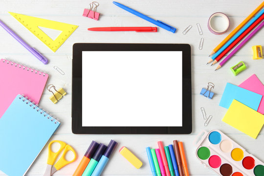 Modern digital tablet and school stationery on a colored background top view. Kontpt back to school. Place for text.