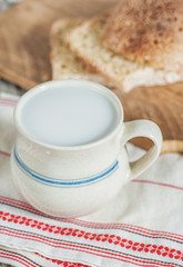 Slices of fresh wheat bread and Cup of milk on vintage tablecloth