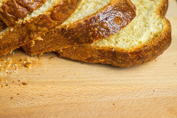 Slice Brioche toast loaf with bread crumbs on wood cutting board