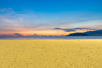 Horizon at colorful sunrise on the beach with yellow sand and blue sky