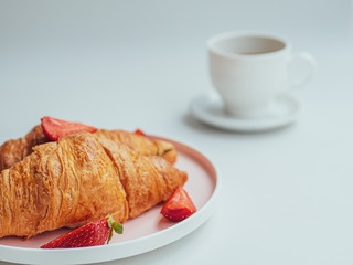 Breakfast with croissants, fresh summer strawberry, and a cup of coffee. Closeup