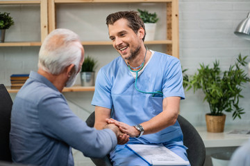 Happy doctor greeting his mature patient while being in a home visit.