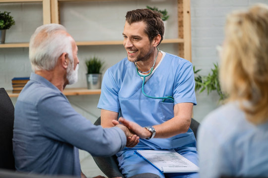 Happy Healthcare Worker And Mature Patient Handshaking During A Home Visit.