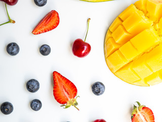Top view colorful summer fruits. Flat lay with mango, strawberry, and cherry on white background
