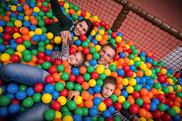 parents and kids playing in the pool with colorful balls