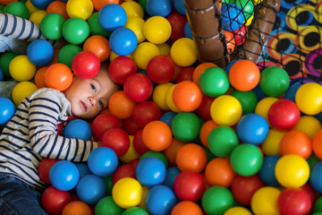 boy having fun in pool with colorful balls