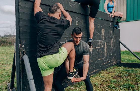 Group of participants in an obstacle course climbing a wall