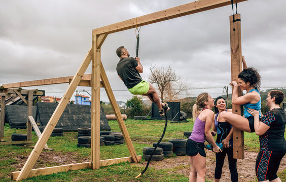 Participants in a obstacle course doing pegboard obstacle and climbing rope