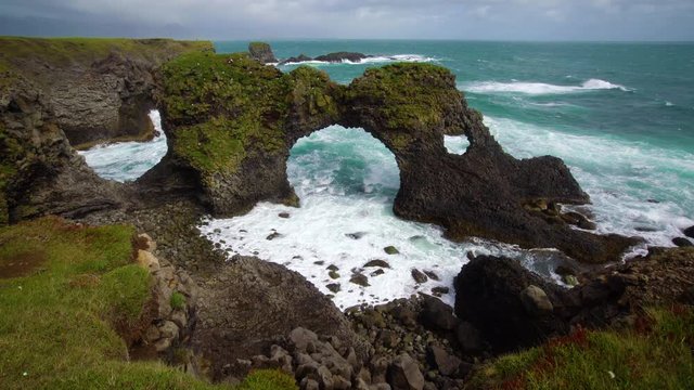 Amazing stone arch Gatklettur basalt rock on Atlantic coast of Arnarstapi in Iceland. The famous natural form arch attracts tourist to visit west of Iceland.