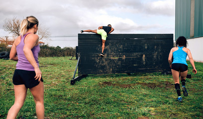 Group of participants in an obstacle course climbing a wall