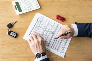 Obraz premium cropped view of car dealer holding pen near contract, calculator, toy car and car key