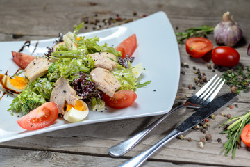 Caesar salad in a beautiful author's presentation from the sheva on a square plate on a wooden background