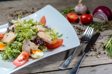 Caesar salad in a beautiful author's presentation from the sheva on a square plate on a wooden background