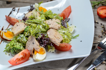 Caesar salad in a beautiful author's presentation from the sheva on a square plate on a wooden background