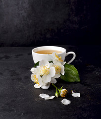 Obraz na płótnie Canvas Jasmine flowers and cup of healthy tea on a black background. Herbal medicine