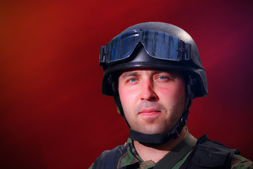 Portrait of a military soldier wearing a helmet, with glasses protecting his eyes from fragmental...